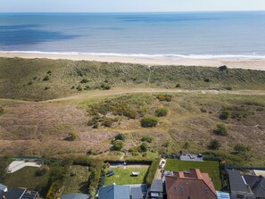 An aerial view of a coastal area with a beach, grassy terrain, and residential buildings. - Norfolk Broads and Coast, The Beach House (Winterton on Sea)