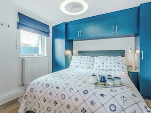 A bedroom with a bed, a window with a view, and blue cabinets. - Norfolk Broads and Coast, The Beach House (Winterton on Sea)