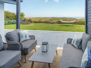 A patio with outdoor furniture, a hammock, and a view of the ocean.