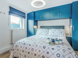 A bedroom with a bed, a window with a view, and blue cabinets. - Norfolk Broads and Coast, The Beach House (Winterton on Sea)