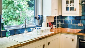 A kitchen with a window, white cabinets, a sink, and a stove. - 3 bedroom accommodation in Keswick (Keswick)