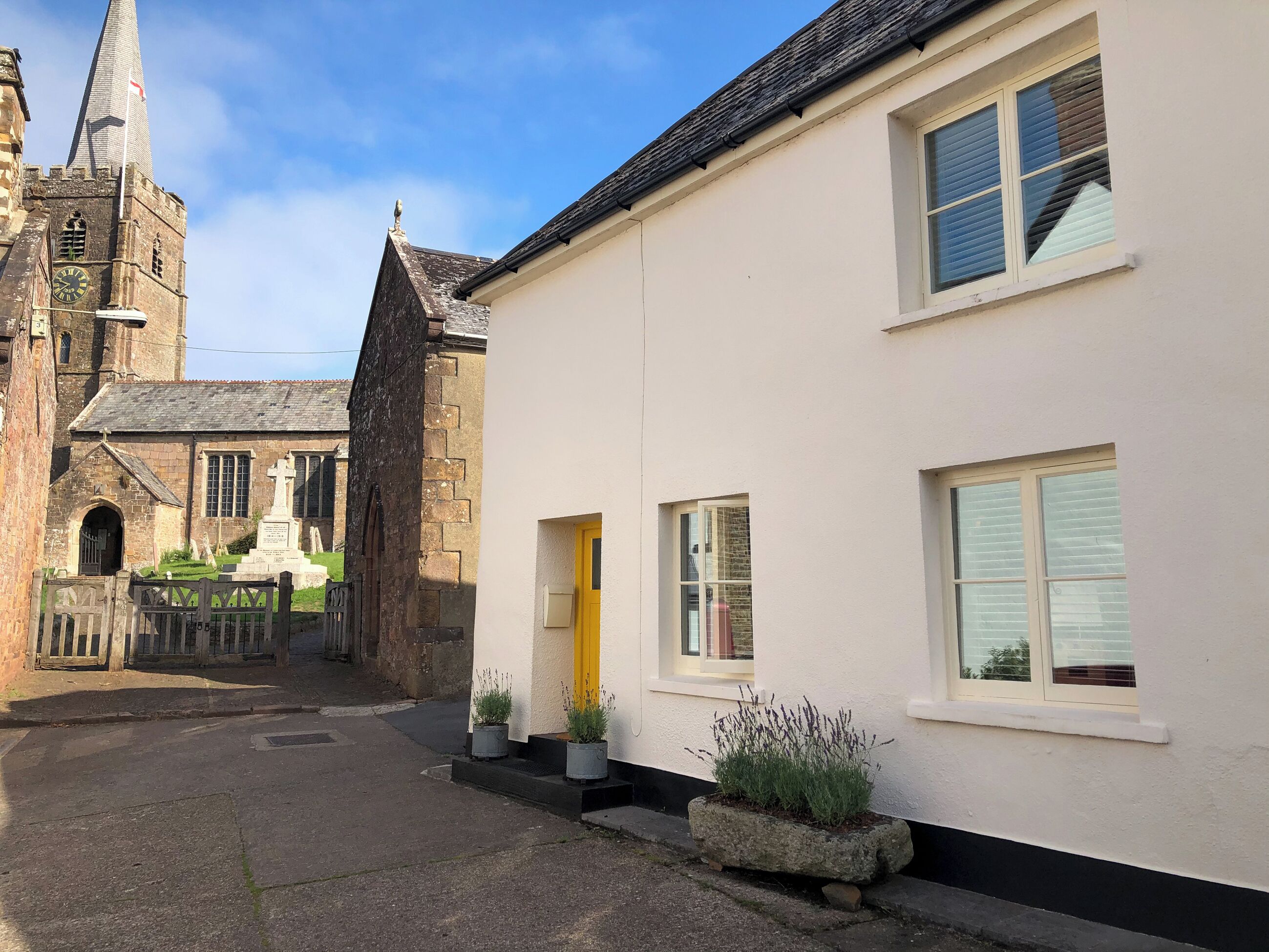 A narrow street with a church and a white building with a yellow door.