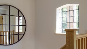A staircase with wooden railings and a window with a brick wall outside.