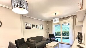 Una sala de estar moderna con un sofá, sillas, una mesa de centro y un ventanal con vistas a zonas verdes.