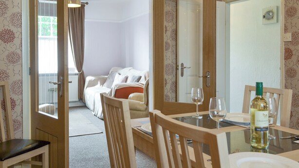 A dining area with a table set for two, a bottle of chardonnay, and a chair. - 2 bedroom accommodation in Filey (Filey)