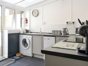 Una cocina moderna con lavadora, un lavamanos, una tetera y un reloj en la pared.
