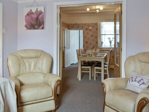 A dining area with a table set for four, surrounded by two leather armchairs.