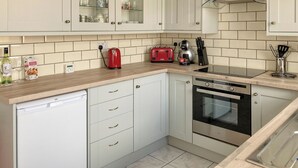 A modern kitchen with white cabinets, a red toaster, a kettle, and a dishwasher. - 3 bedroom accommodation in Buxton (Buxton)