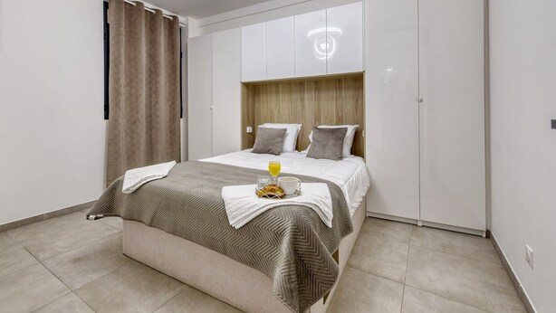 Une chambre à coucher moderne avec un lit, une table de chevet et une tête de lit.