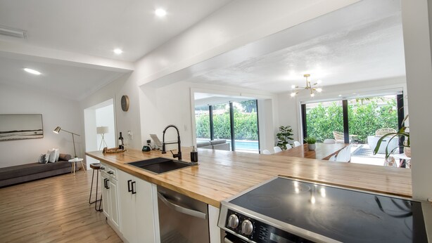 A modern kitchen with a wooden countertop, stainless steel appliances, and a large window offering a view of the outdoors. - Boho Chic House-POOL & FIREPIT - 15 mins to South Beach (El Portal)