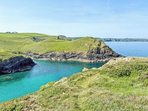 A coastal landscape with a clear view of the sea, grassy hills, and rocky cliffs. - The Cottage - UK35177 (Buckland Brewer, near Bideford)