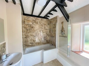 A bathroom with a bathtub, a shower, and a sink.