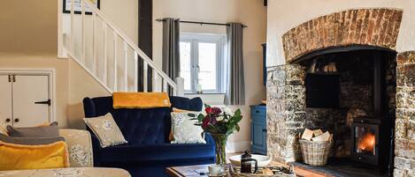 Una sala de estar con chimenea, una escalera y un sofá azul.