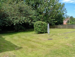 A grassy outdoor area with a hedge and a metal structure.