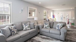 A living room with two grey sofas, a patterned rug, and a large mirror on the wall. - Beachside Gem! Walk to the Beach! Close to Shopping, Dining, & More! (Gulfport)