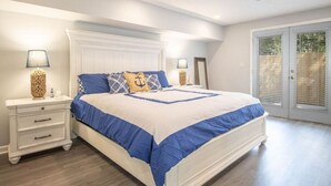 A bedroom with a bed, nightstands, and a door with a view. - Beachside Gem! Walk to the Beach! Close to Shopping, Dining, & More! (Gulfport)