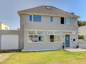 A two-story residential building with a garage, multiple windows, and a front door. - 4 bedroom accommodation in Hayling Island (Hayling Island)