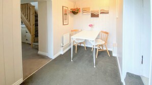A dining area with a white table and chairs, a radiator, and a hanging flower basket.