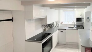 A modern kitchen with white cabinetry, a black stovetop, and a dishwasher.