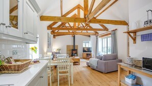 Un vaste espace de vie agrémenté de poutres en bois, d’une cheminée, d’un canapé et d’une table à manger avec des chaises.