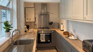 Una cocina moderna con un lavamanos de acero inoxidable, un horno empotrado y una estufa a gas.