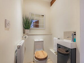 A compact bathroom with a toilet, bidet, and a small window with a plant. - The Barn at Whitefields (Charlton)