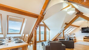 A spacious loft with a dining area, seating, and a television. - The Barn at Whitefields (Charlton)