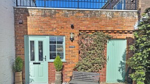 A brick building with a green door, a bench, and potted plants. - 1 bedroom accommodation in Ingham, near Stalham (Ingham, near Stalham)