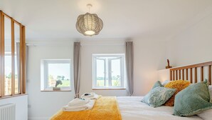 A bedroom with a bed, two windows, a radiator, and a hanging light fixture. - 1 bedroom accommodation in Ingham, near Stalham (Ingham, near Stalham)