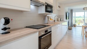A modern kitchen with white cabinetry, a built-in microwave, a kettle, and a toaster. - 1 bedroom accommodation in Ingham, near Stalham (Ingham, near Stalham)