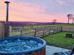 Ein Whirlpool in einem Garten mit Holzzaun und Blick auf die Landschaft.