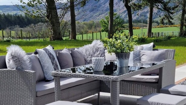 A wicker outdoor seating area with a glass-top table, cushioned sofas, and a potted plant. - 3 bedroom accommodation in Scaniport (Scaniport)
