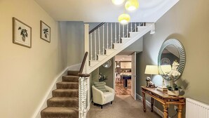 A carpeted staircase with a white railing, a round mirror, a small table with a lamp, and a sofa in a hallway. - 3 bedroom accommodation in Scaniport (Scaniport)