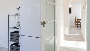 Una cucina moderna con un frigorifero bianco, una scaffalatura in metallo e una pianta pensile.