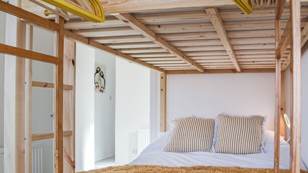 Una camera da letto con soffitto in legno, un letto con cuscini a righe e un tappeto morbido.