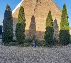 A stone building with a pyramid-like structure, surrounded by neatly trimmed evergreen trees.