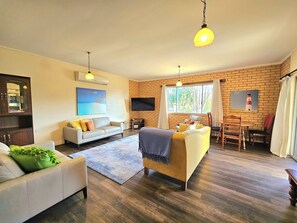 Ein Wohnzimmer mit einer Couch, einem Sessel und einem Essbereich mit Stühlen und einem Tisch.