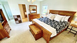 A bedroom with a wooden bed, a dresser, a mirror, and a ceiling fan.