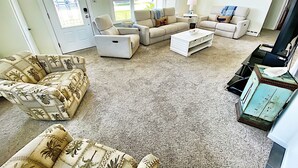 A living room with a beige carpet, two sofas, a coffee table, and a television.