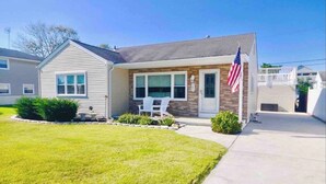 A single-story house with a front porch, a small lawn, and an American flag.