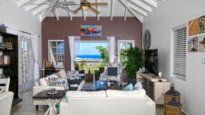 A living room with a sofa, coffee table, and a view of the ocean. - Centrally located minutes away from great beaches, town center and French side. (Philipsburg)