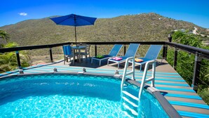 A pool area with lounge chairs, a table, and an umbrella. - Centrally located minutes away from great beaches, town center and French side. (Philipsburg)