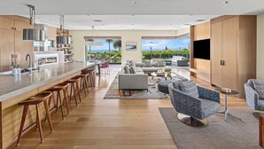 A modern kitchen with a bar area, a dining space, and a living area with a view of the outdoors.