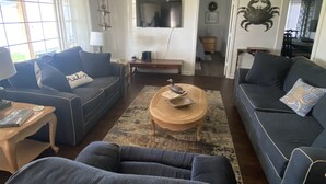 A living room with two sofas, a coffee table, and a TV. - Fin's Fish Camp at Harker's Island (Harkers Island)