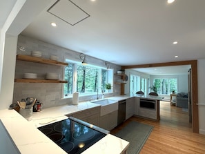 Een moderne keuken met een ingebouwde kookplaat, houten planken en grote ramen.