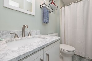 Une salle de bain avec un lavabo en marbre, des toilettes et un rideau de douche.