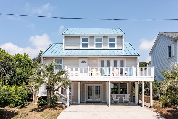 Une maison à deux étages avec un balcon, une véranda couverte à l’avant et un garage.