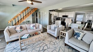 A modern living room with a staircase, a dining area, and a kitchen. - Ocean View House, Steps to Beach, Pet Friendly, Linens & Beach Gear Provided (Surf City)