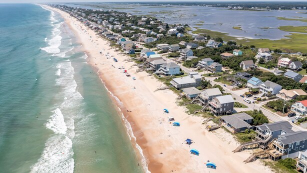 An aerial view of a coastal town with a long sandy beach, houses, and a clear view of the ocean. - Ocean View House, Steps to Beach, Pet Friendly, Linens & Beach Gear Provided (Surf City)