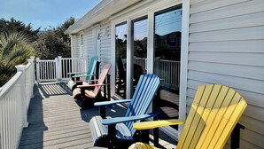 A covered deck with Adirondack chairs and a white railing. - Ocean View House, Steps to Beach, Pet Friendly, Linens & Beach Gear Provided (Surf City)